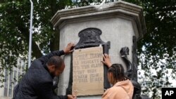 A banner is taped over the inscription on the pedestal of the toppled statue of Edward Colston in Bristol, England, June 8, 2020.