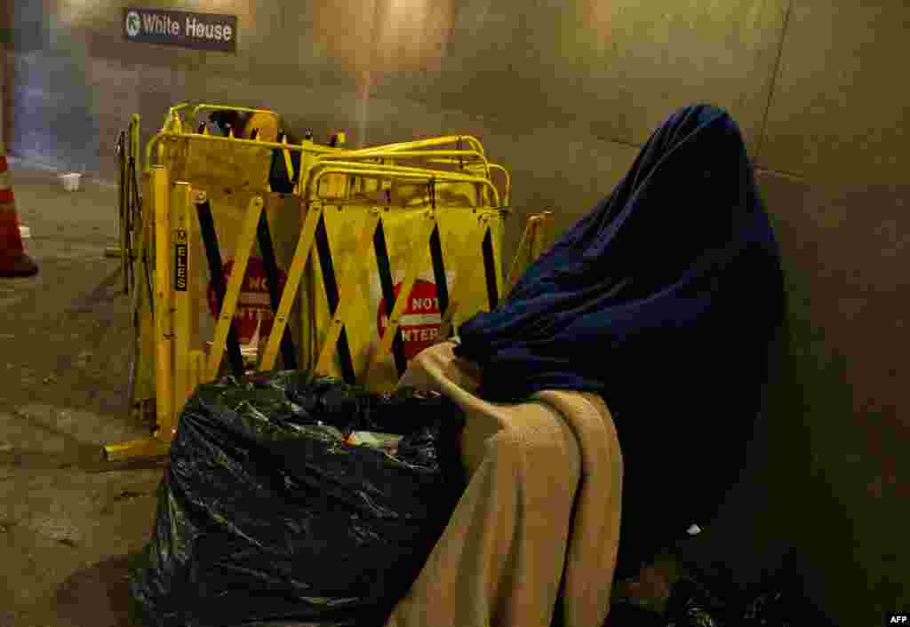 Seorang tunawisma yang kedinginan beristirahat di sebuah stasiun kereta bawah tanah di Washington, DC.