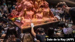 University students clean the Pillar of Shame, a statue by Danish artist Jens Galschiot to remember the victims of the 1989 Tiananmen crackdown in Beijing, at the University of Hong Kong on June 4, 2020.