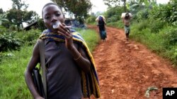 FILE - Ombeni Balihiamwabo,17, stands with his rifle outside a military post in Nyangonbe, Democratic Republic of Congo.