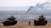Turkish army tanks are seen on the Turkish side of the border as smoke rises from the Syrian town of Kobani Oct. 8, 2014.
