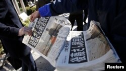 A man (L) receives an extra edition of a newspaper, which reports that Islamic State militants said they had beheaded Japanese journalist Kenji Goto, in Tokyo, Feb. 1, 2015. 