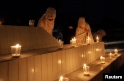 FILE - Women light candles during a candlelight vigil in honor of philanthropst Abdul Sattar Edhi in Quetta, Pakistan, July 9, 2016.