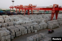 FILE - Workers ride through an aluminum ingots depot in Wuxi, Jiangsu province, China, Sept. 26, 2012. China has recently warned of a "huge impact" on trade as a result of U.S. tariffs on steel and aluminum.