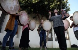 FILE -Young Yazidi and Muslim women, part of the musical group "40 Plaits," rehearse a traditional Kurdish song accompanied by the Daf, a large Kurdish frame drum, in a community center in Dahuk, Iraq, June 25, 2019.