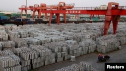FILE - Workers ride through an aluminum ingots depot in Wuxi, Jiangsu province, China, Sept. 26, 2012. On Friday, China warned of a "huge impact" on trade if the U.S. places tariffs on steel and aluminum.