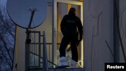A German police officer stands in a smashed glass door of Frankfurt's Bilal mosque during early morning raids in the federal state of Hesse and its capital Frankfurt, Feb. 1, 2017. 