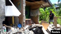 A man stands alongside a building belonging to the World Vision aid organization that was damaged by an earthquake in Kirakira on the Solomon Islands, Dec. 9, 2016.