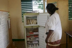 Marguerite Ouangraoua, a nurse at the health clinic in Zeguedessin village on the outskirts of Burkina Faso's capital, Ouagadougou, opens the fridge where the clinic keeps the vaccines, Thursday Oct. 8, 2020. (AP Photo/Sam Mednick)