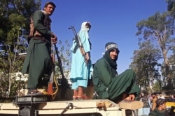 Pejuang Taliban berdiri di atas kendaraan di sepanjang pinggir jalan di Herat, kota terbesar ketiga di Afghanistan. (Foto: AFP)