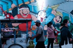 Orang-orang yang memakai masker berjalan pada jam-jam sibuk saat pemerintah memperpanjang pembatasan untuk menekan penyebaran COVID-19 di Jakarta, 21 September 2021. (Foto: REUTERS/Ajeng Dinar Ulfiana)