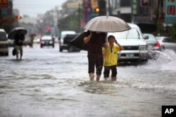 FILE - Local residents walk through floodwaters from passing Tropical Storm.