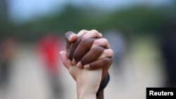 A man and a woman hold hands aloft in Hyde Park during a "Black Lives Matter" protest following the death of George Floyd who died in police custody in Minneapolis, London, Britain, June 3, 2020. 