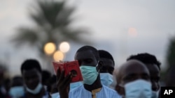 a pilgrim from the Mouride Brotherhood, reads a book with poems written by Cheikh Amadou Bamba as he stands in line to enter at Grand Mosque of Touba in Senegal, Oct. 5, 2020.