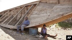 Des survivants assis près d’une pirogue similaire à une autre qui a fait naufrage, à Goma, RDC, 5 septembre 2006.