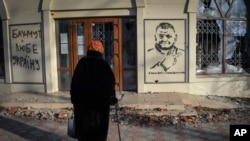 Seorang warga tampak mengamati grafiti yang menampilkan wajah Panglima Militer Ukraina Valery Zaluzhny di salah satu sudut di Kota Bakhmut, pada 20 Desember 2023. (Foto: AP/Andriy Andriyenko)