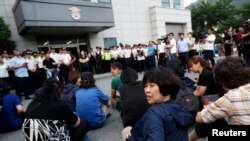 Keluarga korban kapal ferry Sewol duduk di depan sebuah bangunan dimana para awak kapal ditahan pasca dengar pendapat di pengadilan Gwangju, Korea Selatan (10/6).
