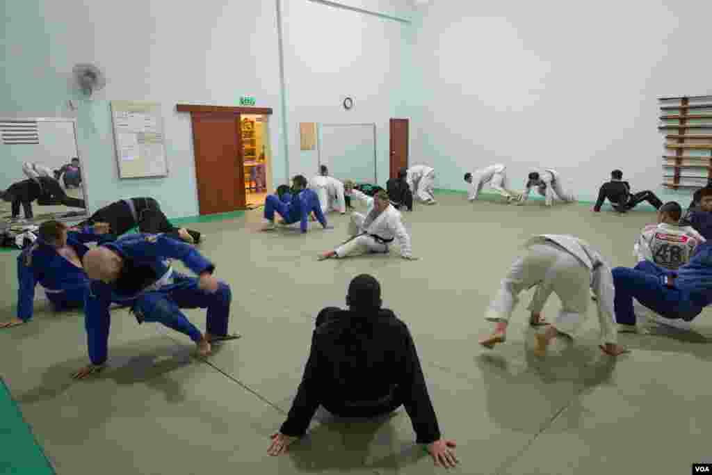 Chris Haueter (in white), one of the well-known BJJ trainers, shows a Jiu Jitsu&#39;s technique to a group of expats during a training at the Olympic Stadium, in Phnom Penh, on February 22, 2016. (Neou Vannarin/VOA Khmer)