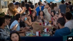 People enjoy in a snack bar in Barcelona, Spain, Sunday, June 21, 2020. Spain ended a national state of emergency after three months of lockdown, allowing its 47 million residents to freely travel around the country for the first time since March 14…