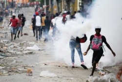 People clash with security forces during a protest to demand the resignation of Haitian President Jovenel Moise, in Port-au-Prince, Haiti, Sept. 30, 2019.