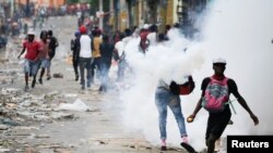 People clash with security forces during a protest to demand the resignation of Haitian President Jovenel Moise, in Port-au-Prince, Haiti, Sept. 30, 2019.