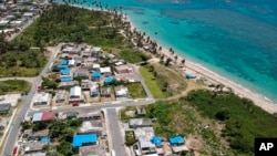 FILE - This June 18, 2018 file photo shows an aerial photo of the Viequez neighborhood, east of San Juan, Puerto Rico, where people were still living in damaged homes, protected by blue plastic tarps, months since Hurricane Maria devastated the island. 