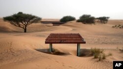 A house's entrance gate is buried under the sand at the Bedouin village of al-Ghuraifabout 100 km, 62 miles, southeast of Sharjah, United Arab Emirates, Sunday, July 9, 2023. (AP Photo/Kamran Jebreili)
