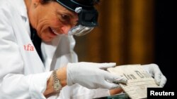 Conservator Pam Hatchfield removes a newspaper from a time capsule, which was placed under a cornerstone of the State House in 1795, at the Museum of Fine Arts, Boston, Massachusetts, January 6, 2015. The capsule was placed by a group of the U.S. founding