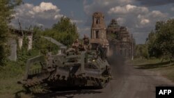 TOPSHOT - Prajurit Ukraina mengoperasikan kendaraan militer lapis baja di jalan dekat perbatasan dengan Rusia, di wilayah Sumy, Ukraina, 14 Agustus 2024. (Roman PILIPEY/AFP)