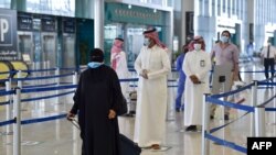 Penumpang Saudi mengantri untuk pemeriksaan suhu di terminal 5 di Bandara Internasional Raja Fahad, yang ditujukan untuk penerbangan domestik, di ibu kota Riyadh pada 31 Mei 2020. (Foto: AFP)