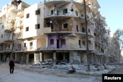 FILE - A man walks past damaged buildings in the rebel held besieged al-Sukkari neighbourhood of Aleppo, Syria, Oct. 19, 2016.