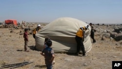 This photo, released by the Syrian Civil Defense, shows the group workers setting up a shelter for civilians who fled from Daraa after shelling by Syrian government forces, in the town of Qunaitra, southwestern Syria, June 28, 2018.