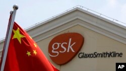 FILE - In this July 24, 2013 file photo, a Chinese flag is hoisted in front of a GlaxoSmithKline building in Shanghai, China.
