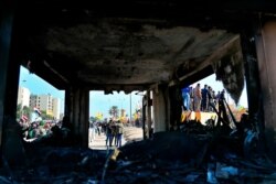 Protesters are seen through broken windows of a burned checkpoint in front of the U.S. embassy in Baghdad, Iraq, Jan. 1, 2020.