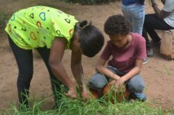 Albertina Naa Adorkor Allotey, a camp facilitator at Under the Mango Tree helps camper Björn Brinkmann harvest some herbs.
