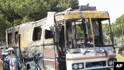 In this picture taken on a government-guided tour, a cameraman works near a destroyed private bus of Libyan leader Moammar Gadhafi at an area in the Bab al-Aziziyah compound in Tripoli, June 27, 2011.