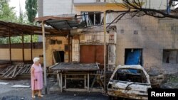 2024年7月22日，在俄罗斯控制的乌克兰顿涅茨克地区，一名妇女走在最近发生的炮击现场。由俄罗斯扶立的地方当局称炮击是乌克兰方面实施的军事打击。(路透社照片)