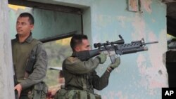 FILE - Police officers take cover during an attack by rebels of the Revolutionary Armed Forces of Colombia (FARC) in Toribio, southern Colombia, July 7, 2012.