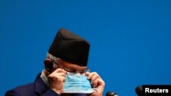 Nepal's Prime Minister Khadga Prasad Sharma Oli, also known as K.P. Oli, puts on a new face mask during his speech before a confidence vote at the parliament in Kathmandu, Nepal May 10, 2021.