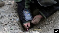 FILE - An Afghan Army soldier searches for land mines with a metal detector during an exercise on defusing improvised explosive devices in Jalalabad, east of Kabul, Afghanistan.