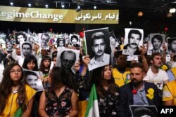 People hold pictures of relatives killed by the Mohllas regime, during "Free Iran 2018 - the Alternative" event, June 30, 2018 in Villepinte, north of Paris during the Iranian resistance national council (CNRI) annual meeting.