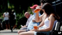People sit in front of a pub that sells take-out drinks, in London, Britain, June 23, 2020. 