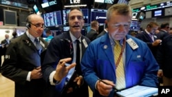 Traders Andrew Silverman, Gregory Rowe, and James Lamb, left to right, work on the floor of the New York Stock Exchange, Aug. 15, 2019. 