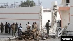 Somali government forces assess the scene of a suicide car explosion in front of the SYL hotel in the capital Mogadishu, Jan. 22, 2015. 