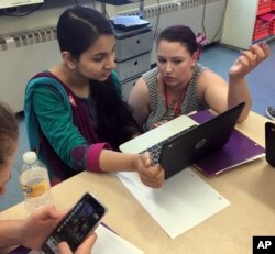 FILE - Teacher Gianna Gurga, right, talks with student Maisha Chowdhury Jabia in a class on financial literacy at Dag Hammarskjold Middle School in Wallingford, Connecticut, May 23, 2018.