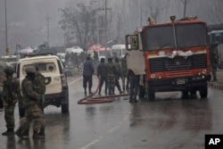 Indian firemen spray water on a road to wash away blood after an explosion in Pampore, Indian-controlled Kashmir, Thursday, Feb. 14, 2019.