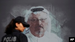 Arhiva - Turska policajka ispred fotografije ubijenog saudijskog novinara Džamala Kašogija ispred konzulata Saudijske Arabije u Istanbulu, tokom obeležavanja godišnjice njegovog ubistva, 2. oktobra 2019.