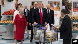 President Donald Trump pushes a cart during a tour of the Church of Jesus Christ of Latter-Day Saints Welfare Square food distribution center, Dec. 4, 2017, in Salt Lake City.
