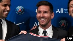 Le président qatari du Paris Saint-Germain Nasser Al-Khelaifi (L) et le directeur sportif du Paris Saint-Germain Leonardo Nascimento de Araujo (R) posent aux côtés du joueur de football argentin Lionel Messi (C) alors qu'il brandit son maillot numéro 30 l