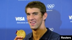 FILE - Michael Phelps poses with his gold medal for the 4x100m medley relay during a news conference with his sponsors at the London 2012 Olympic Games, August 5, 2012. 